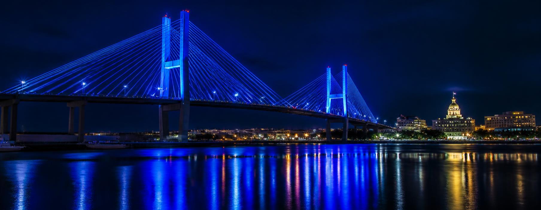 Savannah bridge lit in blue at night over the river